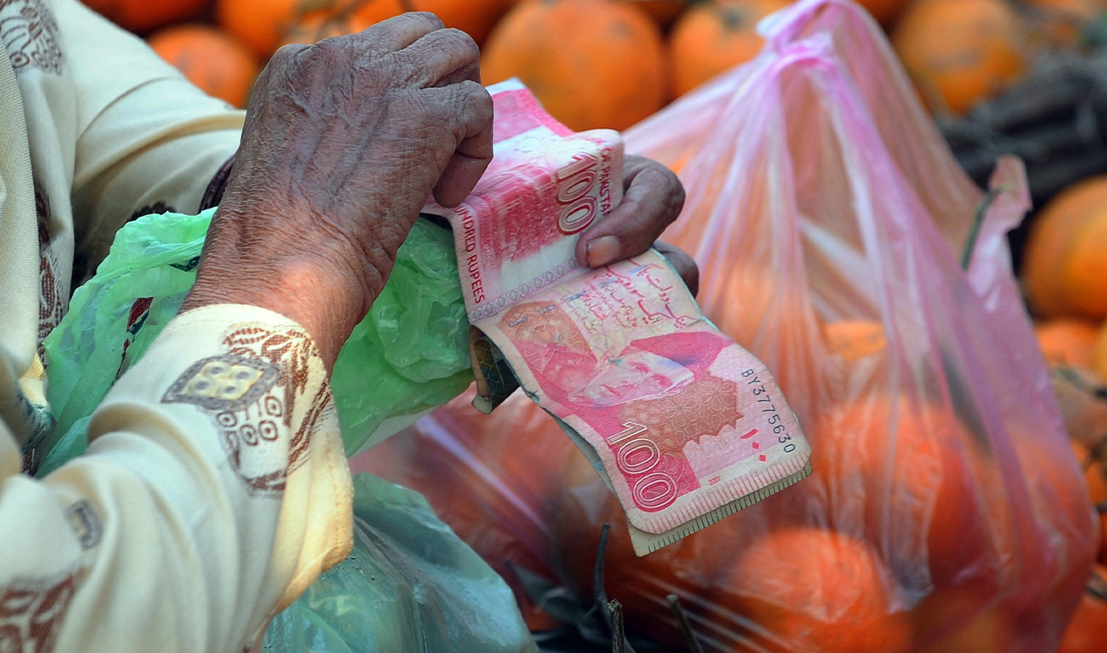 An elderly woman counts Pakistani currency notes at a fruit market in Lahore on December 14, 2011. (AFP/File)