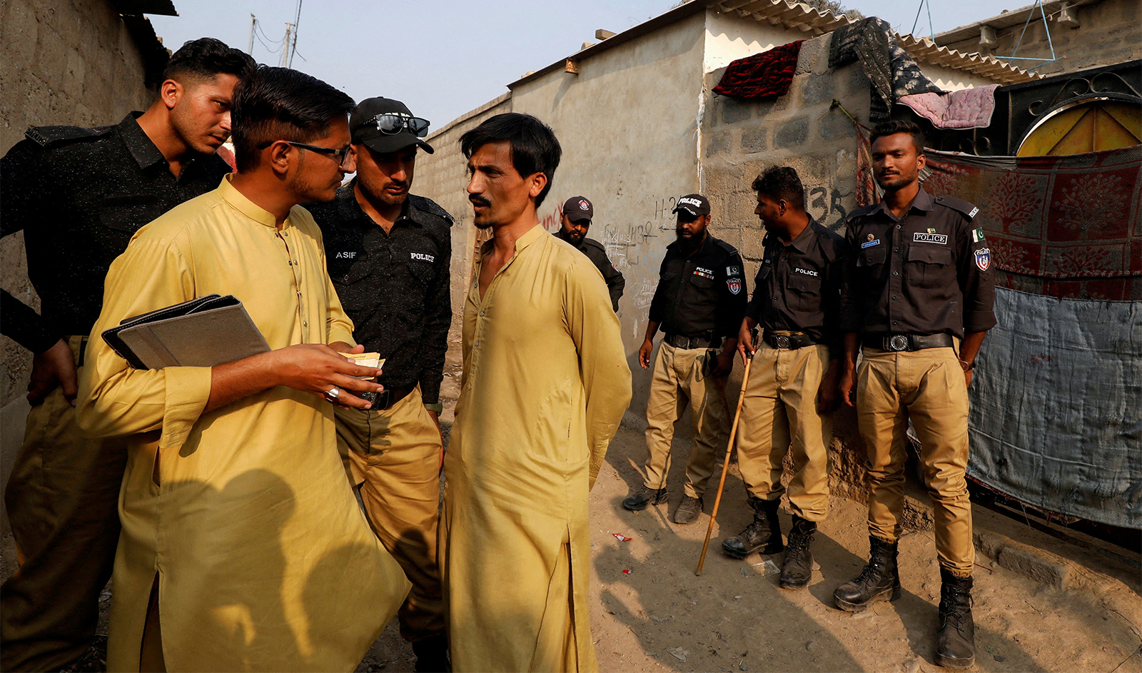 A worker from the National Database and Registration Authority (NADRA), along with police officers, speaks to an Afghan citizen while checking identity cards, during a door-to-door search and verification drive for undocumented Afghan nationals, in an Afghan Camp on the outskirts of Karachi, Pakistan, on November 21, 2023. (REUTERS)