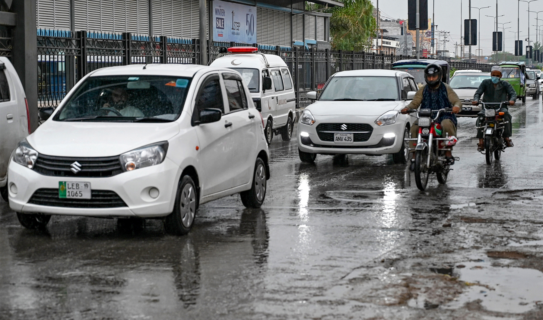 Commuters ride along a street after rainfall in Peshawar on June 5, 2024. (AFP/File)