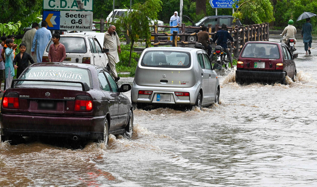 Commuters drive across a flooded street after heavy monsoon rains in Islamabad on July 10, 2024. (AFP)