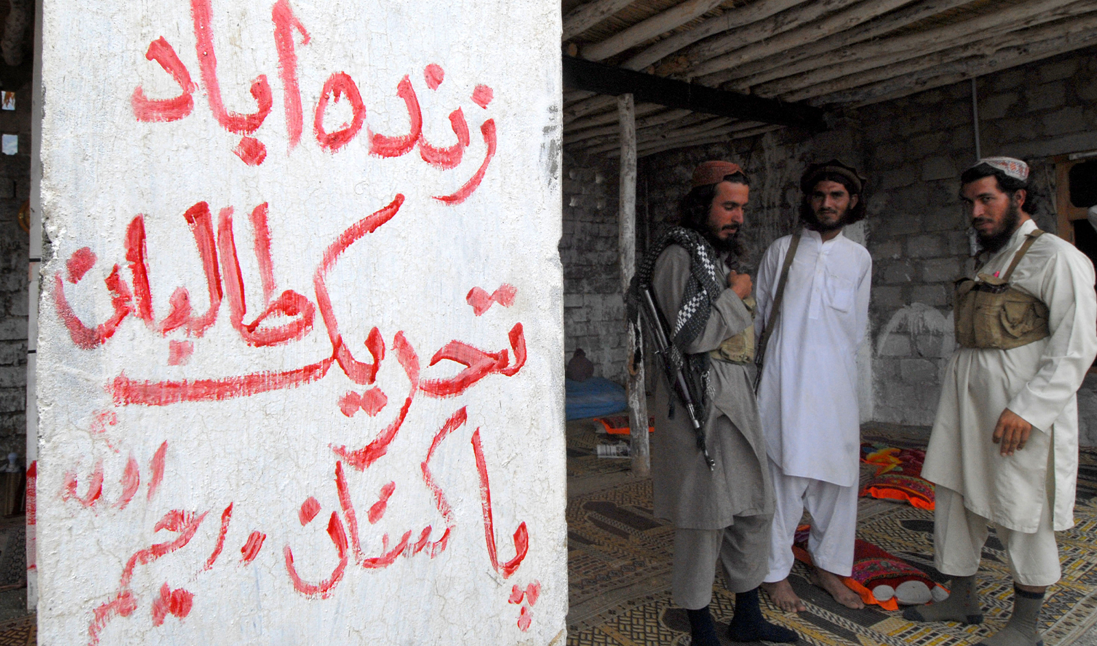 Armed militants of Tehreek-e-Taliban Pakistan (TTP), stand next to a graffiti which read as "Long Live Tehreek-e-Talban Pakistan" at a camp in a Pakistani tribal district of Mohmand Agency on July 21, 2008. (AFP/File)