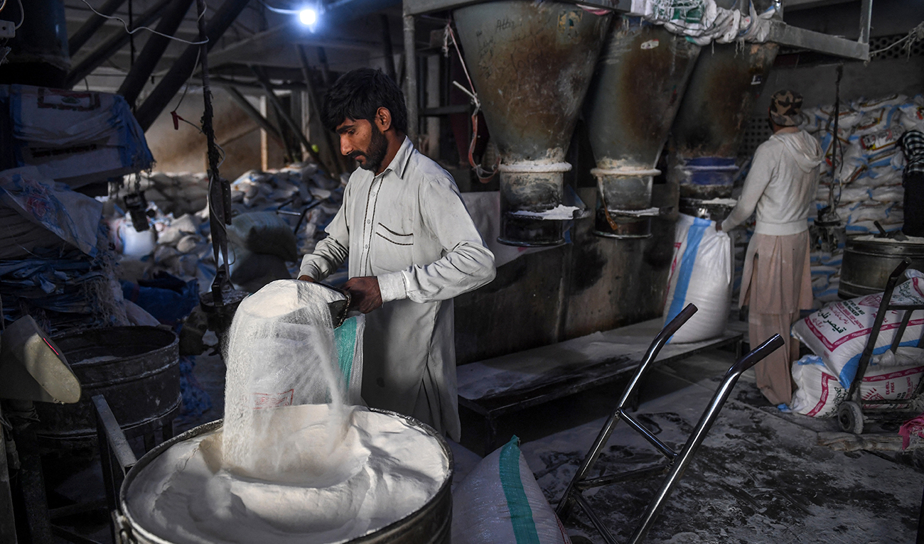 Workers fill sacks with wheat flour at a mill in Karachi on January 21, 2020. (AFP/File)