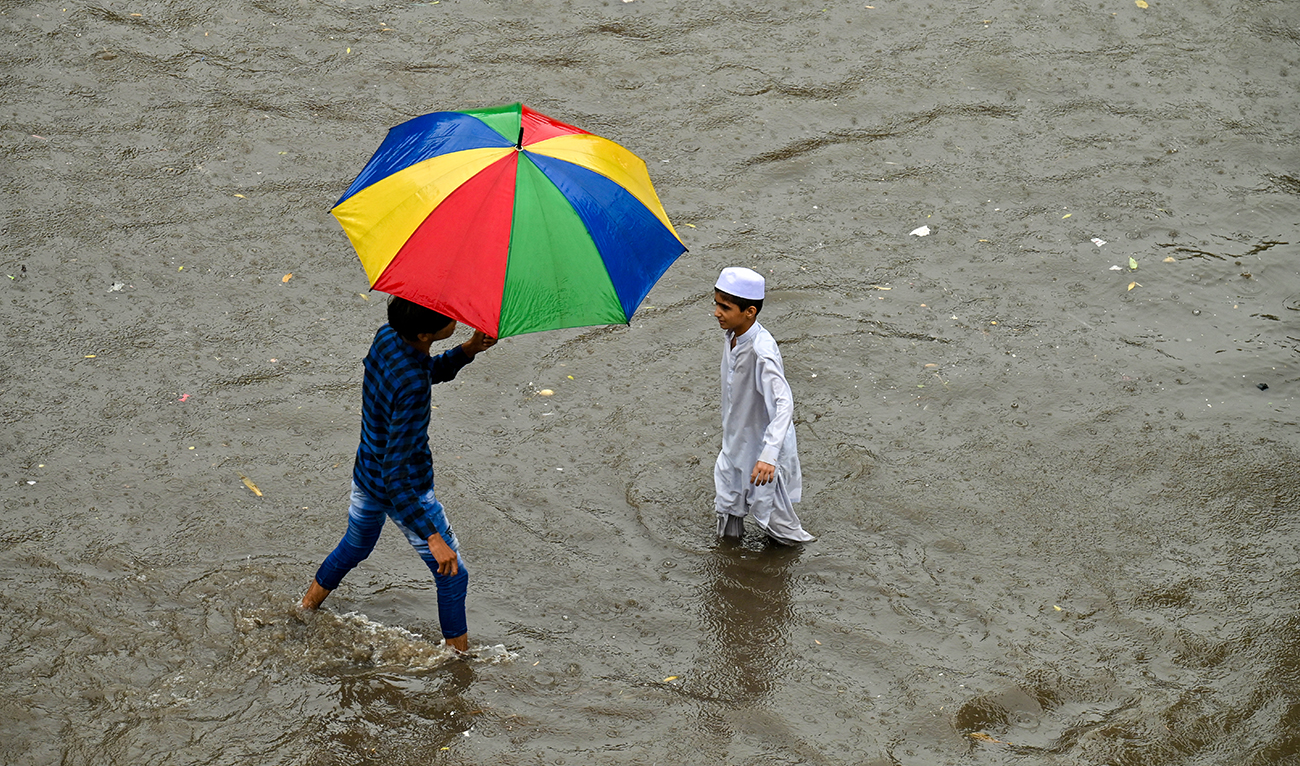 People wade across a flooded street amid heavy rainfall in Lahore on July 12, 2024. (AFP/File)