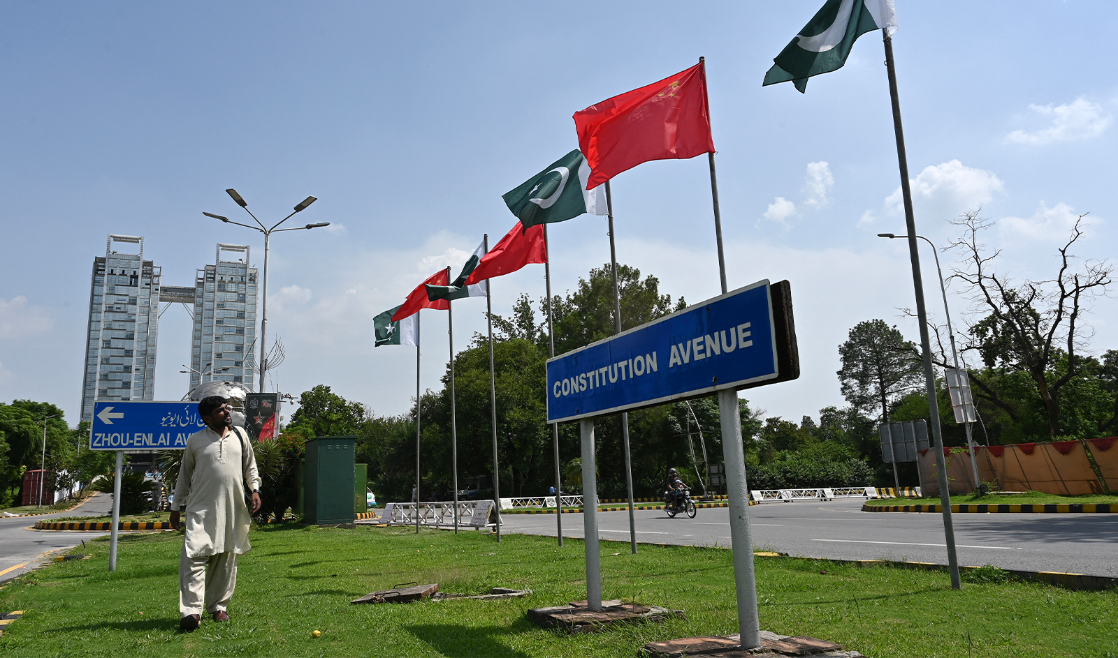 A man walks past China's and Pakistani national flags installed on the constitution avenue ahead of the visit of Chinese Vice Premier He Lifeng, in Islamabad on July 30, 2023. (AFP/File)