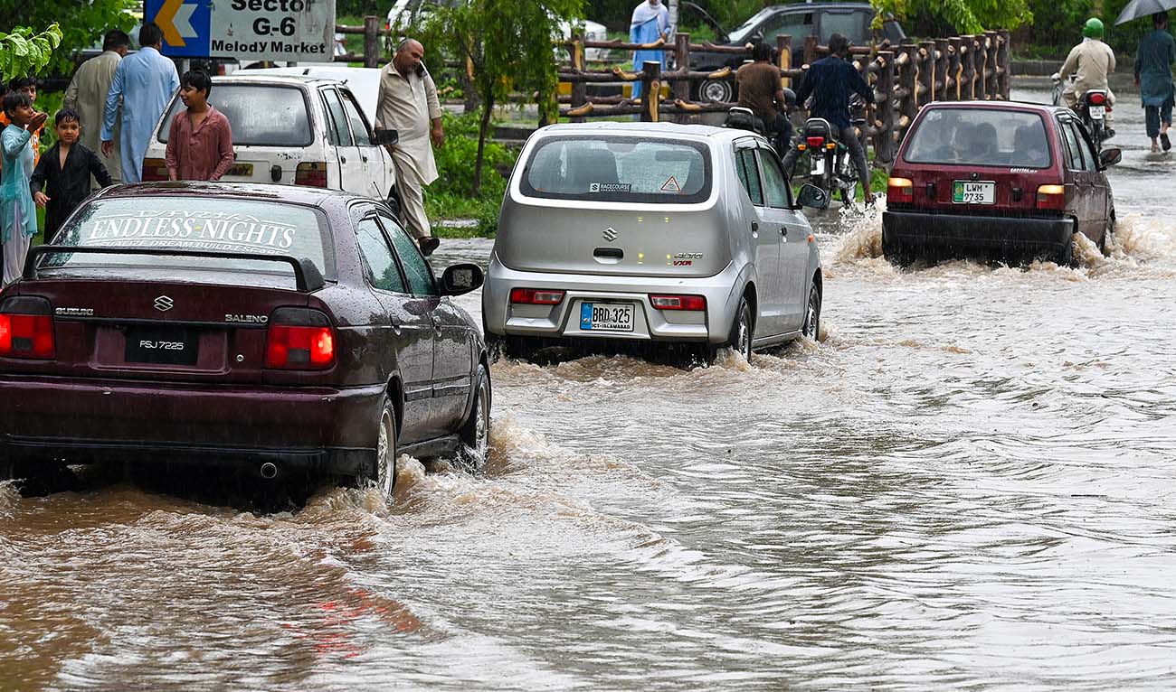 Commuters drive across a flooded street after heavy monsoon rains in Islamabad on July 10, 2024. (AFP/File)