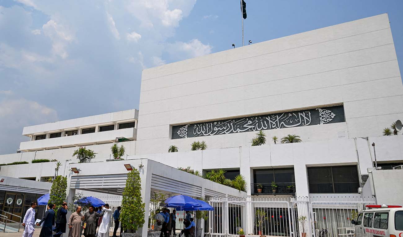 People stand outside the Parliament house during a budget session in Islamabad on June 26, 2024. (AFP/File)