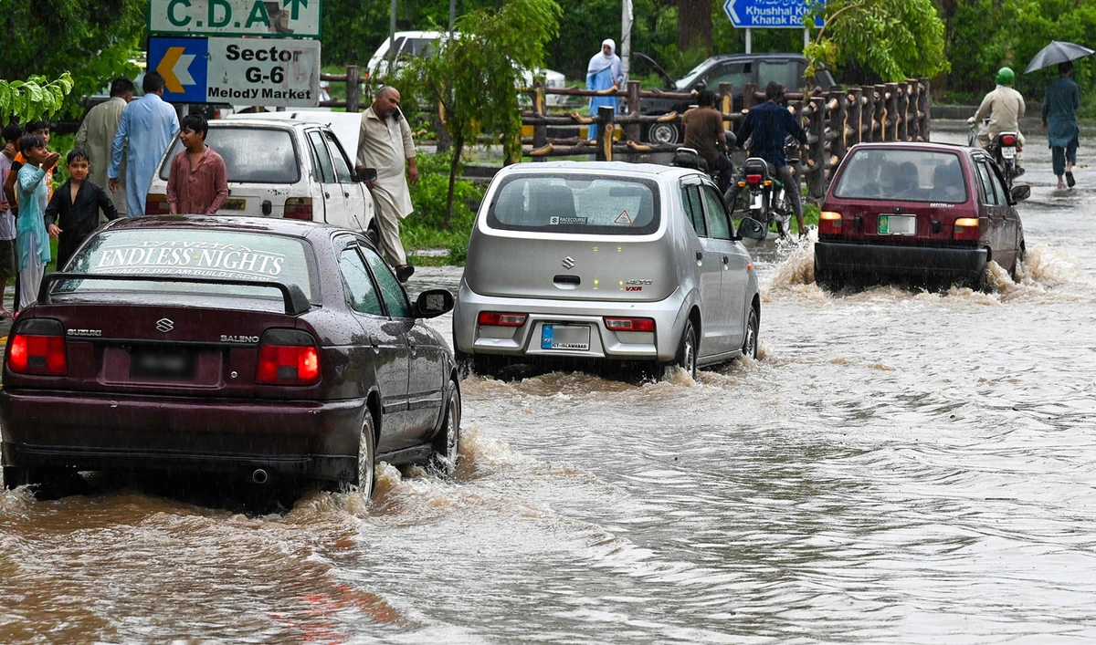 Commuters drive across a flooded street after heavy monsoon rains in Islamabad on July 10, 2024. (AFP)