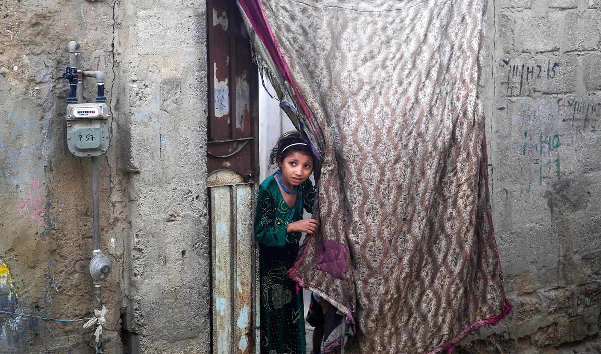 An Afghan refugee girl peeps out during a search operation to identify alleged illegal immigrants, on the outskirts of Karachi on November 17, 2023. (AFP)