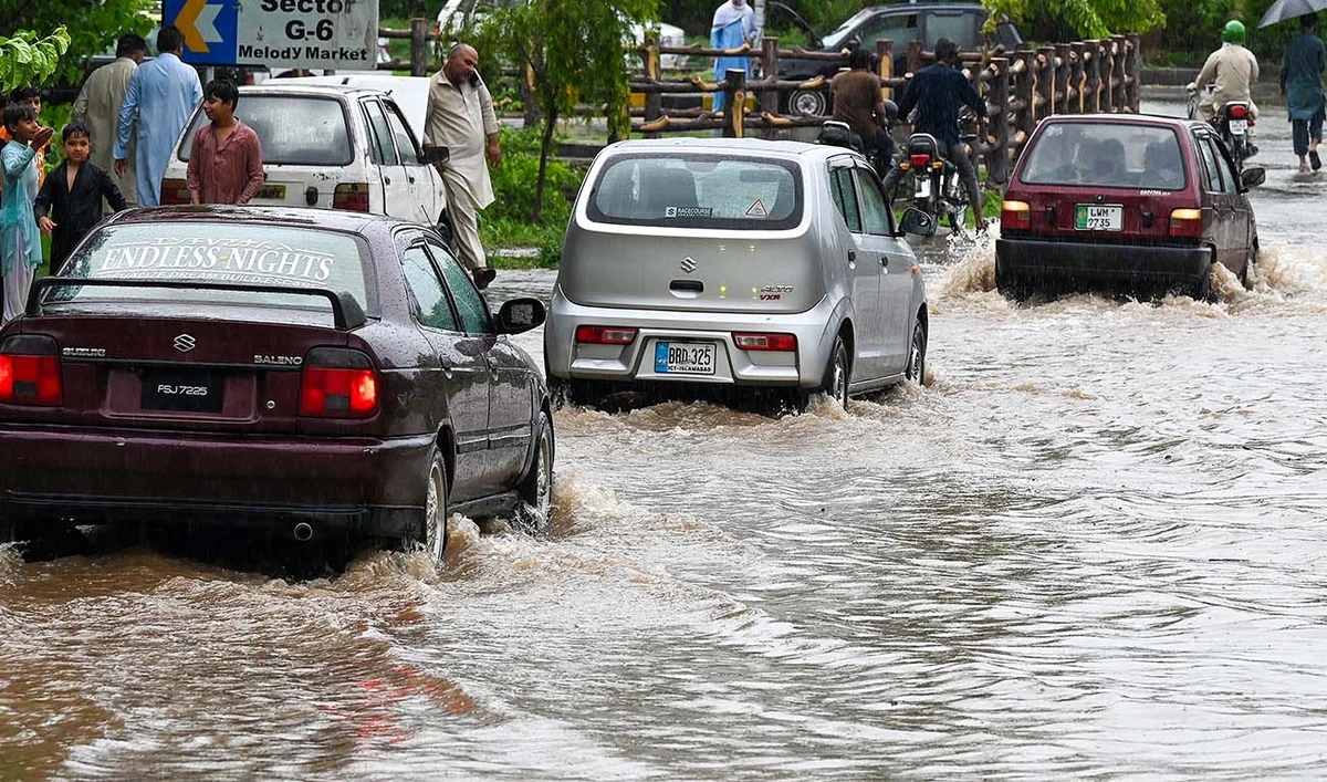 Commuters drive across a flooded street after heavy monsoon rains in Islamabad on July 10, 2024. (AFP/File)