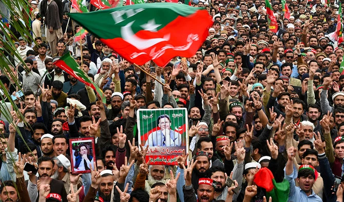 In this file photograph, taken on March 10, 2024, Pakistan Tehreek-e-Insaf (PTI) party supporters hold portraits of Pakistan’s former prime minister Imran Khan, as they protest against the alleged skewing in Pakistan’s national election, in Peshawar. (AFP/File)