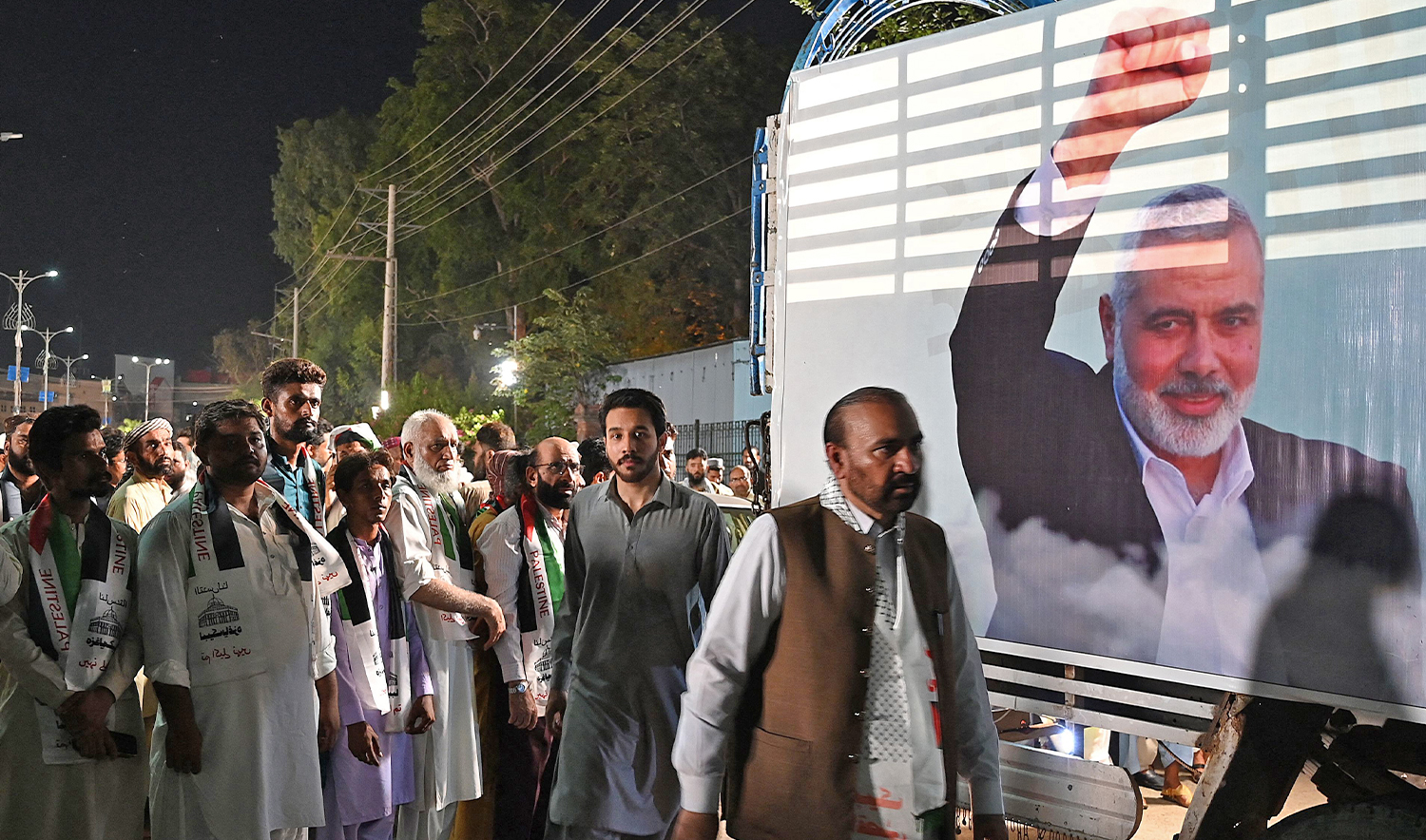 Activists and supporters of Pakistan's Jamaat-e-Islami (JI) party attend an absentee funeral prayers for slain Hamas political leader Ismail Haniyeh, next to his poster in Rawalpindi on July 31, 2024, following his assassination in an air strike in Tehran. (AFP)