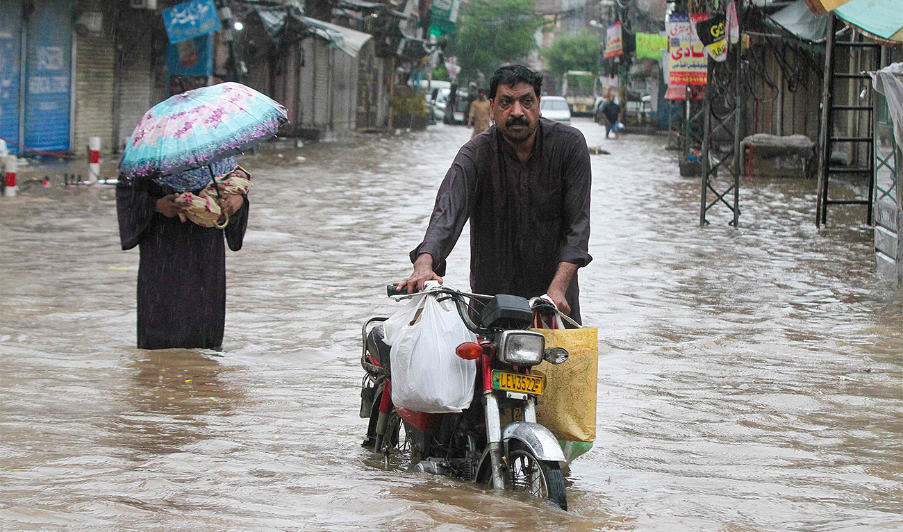 A man wades through a flooded street during heavy rainfall in Lahore on August 1, 2024. (AFP)