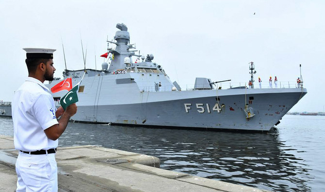 In this handout photograph, taken and released by Director General Public Relations Pakistan Navy on July 30, 2024, Pakistan Navy official holds national flags of Pakistan and Turkiye as Turkish Navy Ship TCG KINALIADA (F-514) arrived in Karachi. (Photo courtesy: Pakistan Navy)