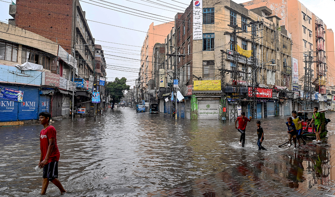 People wade through a flooded street amid heavy rainfall in Lahore on July 28, 2024. (AFP/File)