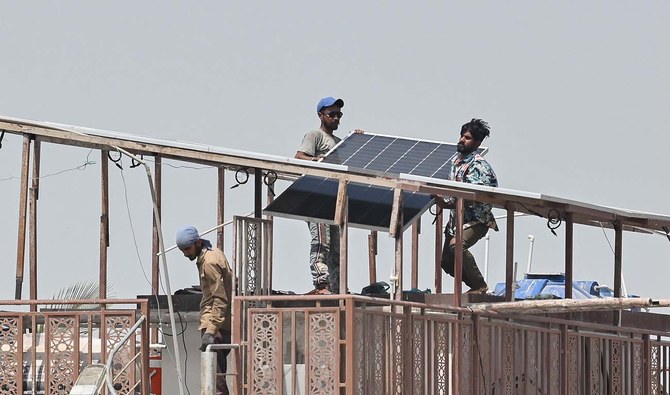 Technicians install solar panel plates on the rooftop of a house on a hot summer day in Karachi on May 27, 2024. (AFP/File)