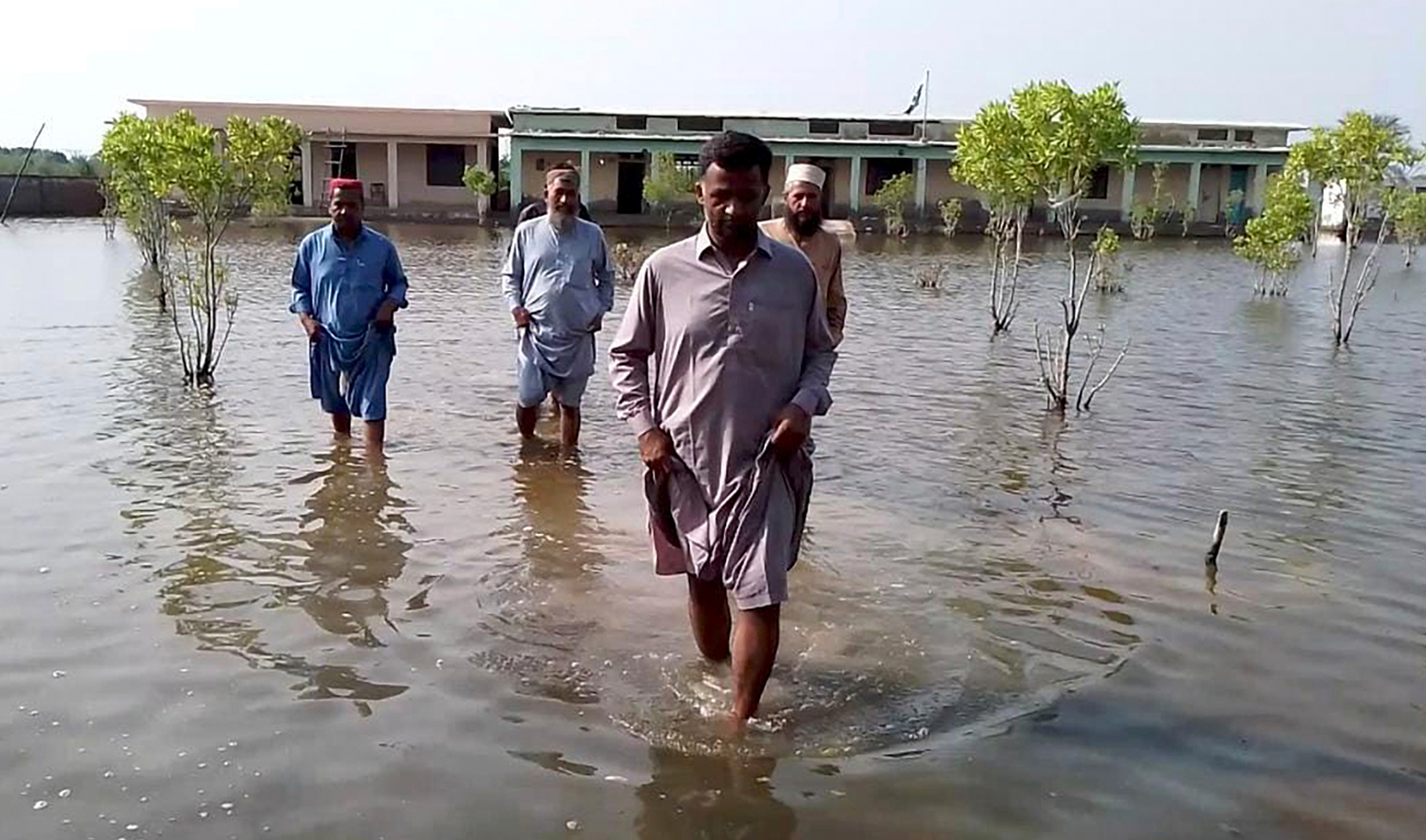 Villagers wade through flood area caused by heavy monsoon rains near Sohbat Pur, an area of Pakistan’s southwestern Baluchistan province on August 19, 2024. (AP)