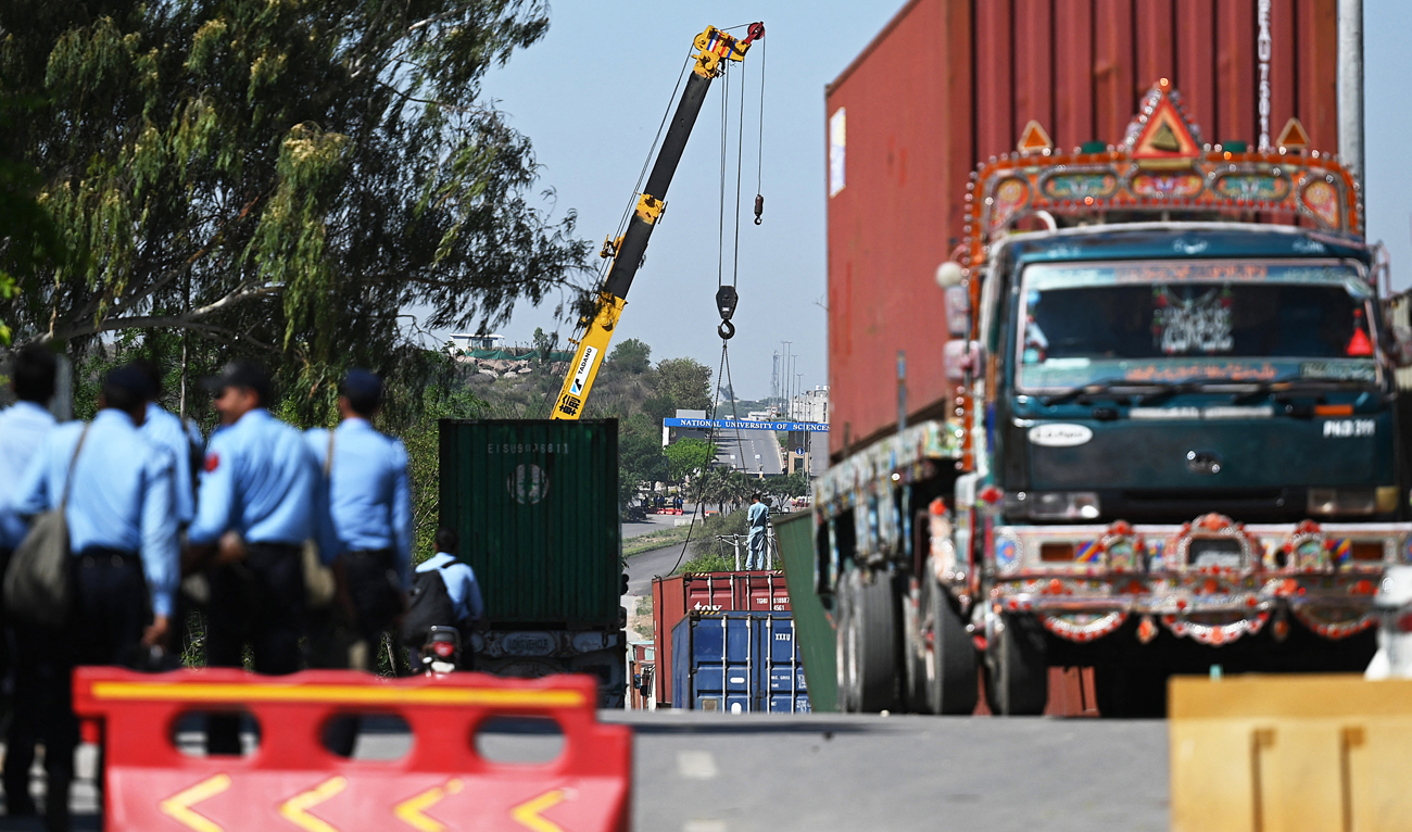 In this file photo, taken on May 10, 2023, police officials use a crane to place shipping containers to block a road outside the police headquarters in Islamabad. (AFP/File)