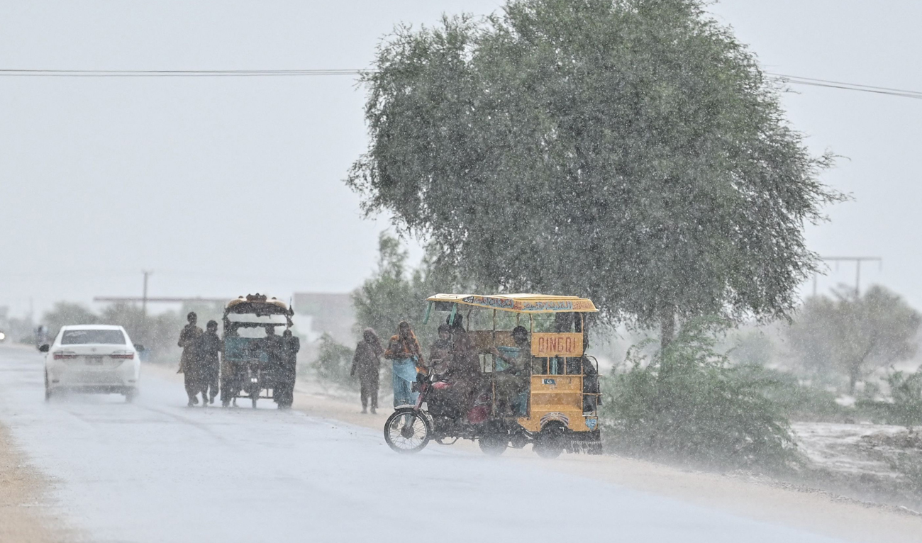 Commuters make their way along a street during rainfall on the outskirts Dadu on August 4, 2024. (AFP/File)