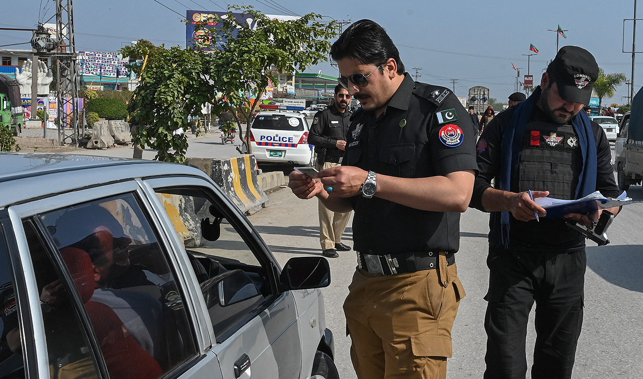 Security personnel search for documents at a checkpoint during the Islamic holy month of Ramadan in Peshawar on March 14, 2024. (AFP/File)