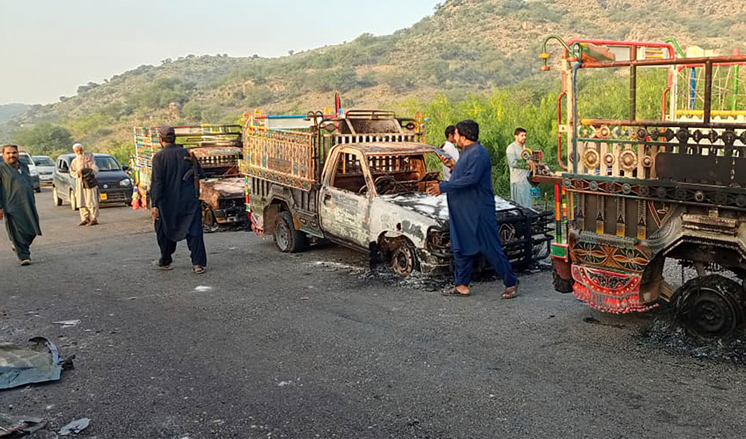 People look burnt vehicles, torched by gunmen after killing passengers, at a highway in Musakhail, a district in Balochistan province in southwestern Pakistan, on August 26, 2024. (AP)