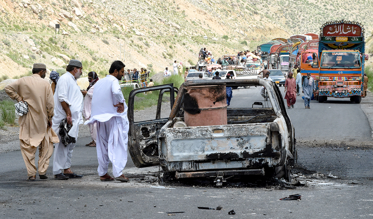 People look at a charred vehicle near a collapsed railway bridge the morning after a blast by separatist militants at Kolpur in Bolan district, Balochistan province on August 27, 2024. (AFP)