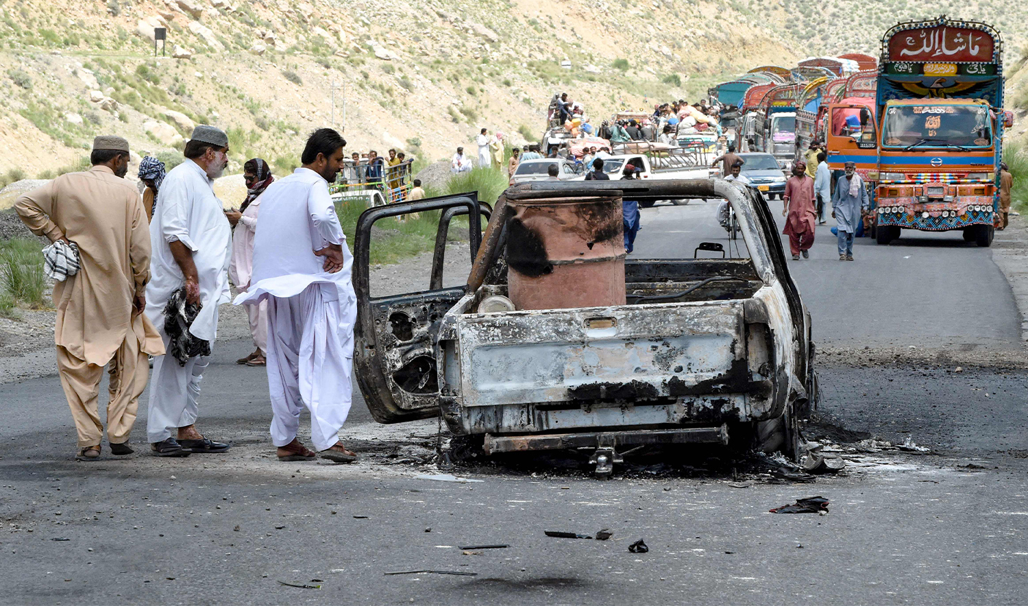 People look at a charred vehicle near a collapsed railway bridge the morning after a blast by separatist militants at Kolpur in Bolan district, Balochistan province on August 27, 2024. (AFP)