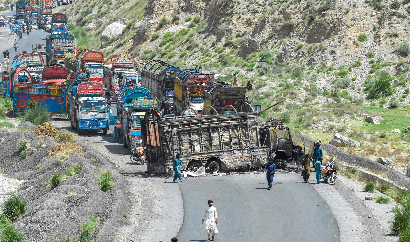People look at a charred vehicle near a collapsed railway bridge a day after a blast by separatist militants at Kolpur in Bolan district, Balochistan province on August 27, 2024. (AFP)