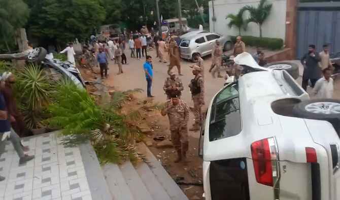 In this screengrab, taken from a video posted on social media platform X, security personnel gather as vehicle lies upside down after an accident in Karachi on August 19, 2024. A high-profile hit-and-run case that claimed two lives, according to police. (X/@MkashanBhatti_)