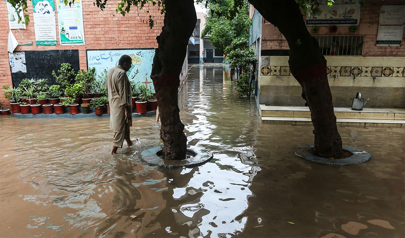 A man walks through floodwaters in the compound of a school, temporarily closed after heavy monsoon rains, in Multan on August 28, 2024. (AFP)