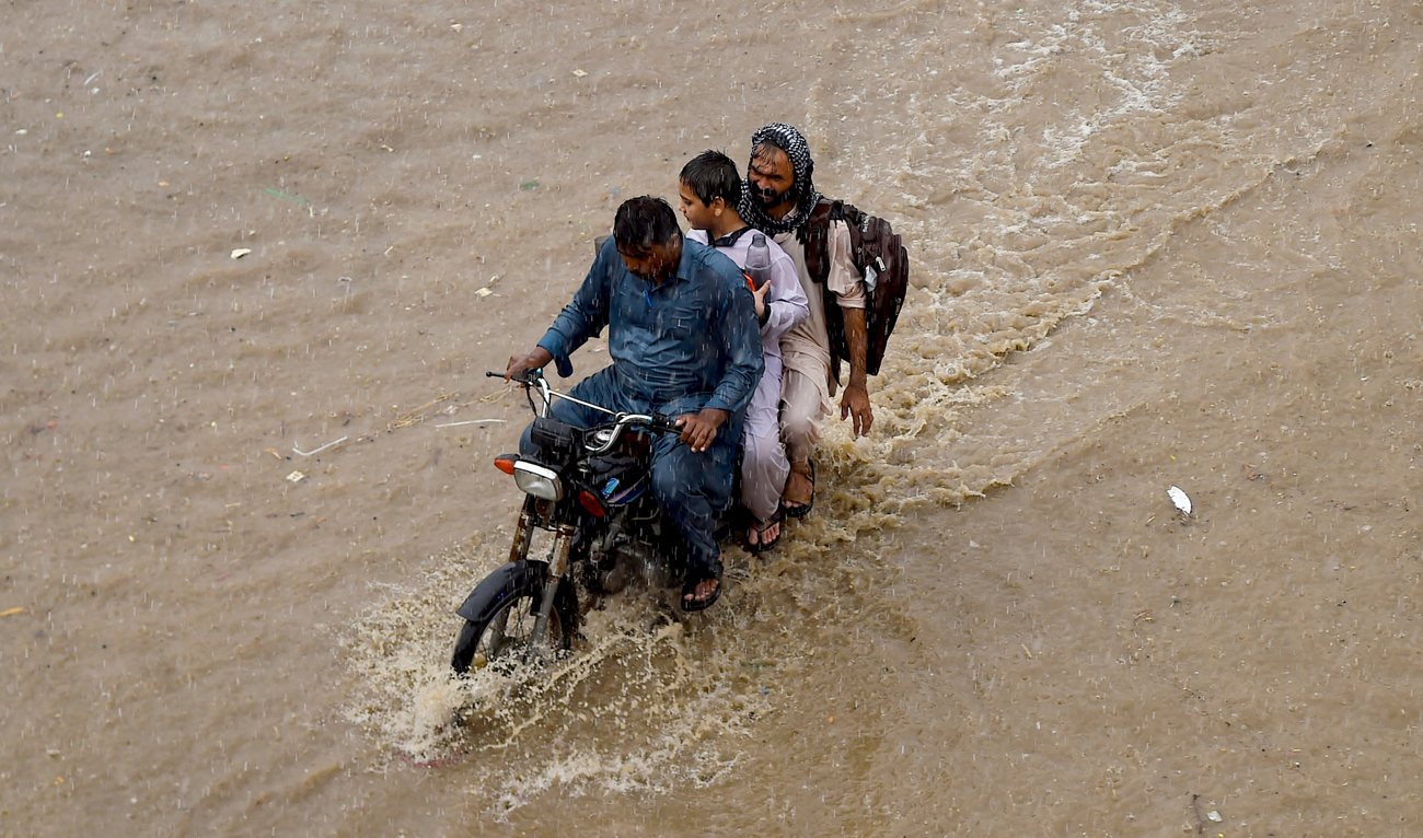 In this file photo, taken on July 30, 2024, people wade through a flooded street amid rainfall in Karachi. (AFP/File)