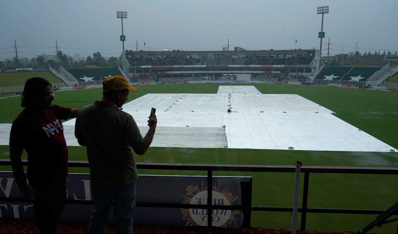 Members of media use their mobile to film the ground which is covered with sheets due to rain as they wait for the start of first day game of second test cricket match between Pakistan and Bangladesh, in Rawalpindi on August 30, 2024. (AP)