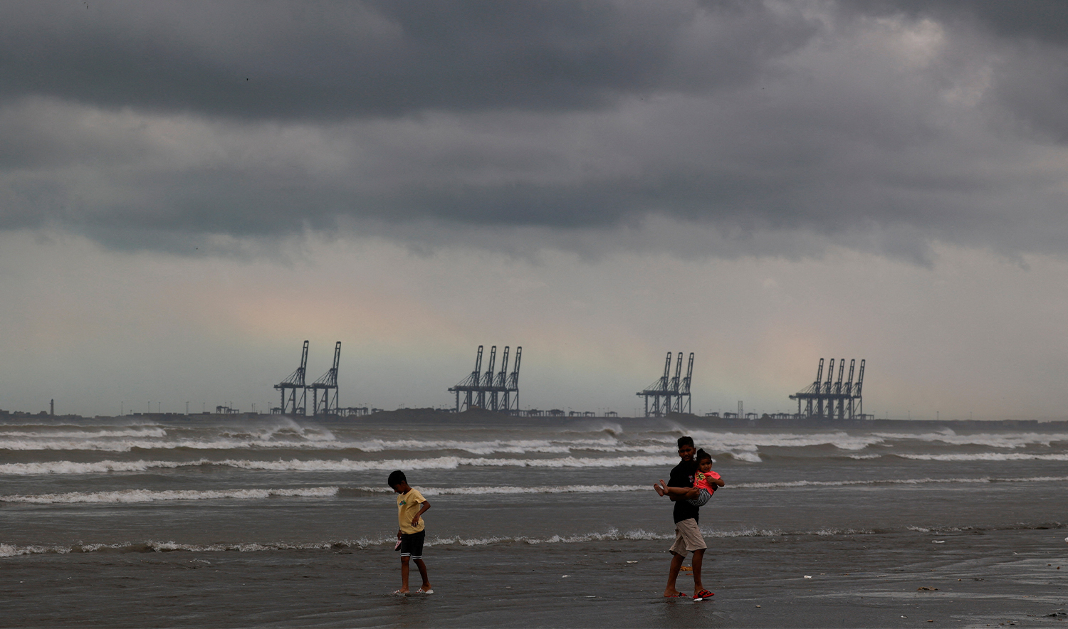 Children play, with the rainbow and rain clouds in the background, following reports from the Pakistan Meteorological Department of a potential cyclonic storm that could develop over the Arabian Sea, at Clifton Beach in Karachi, Pakistan on August 30, 2024. (REUTERS)