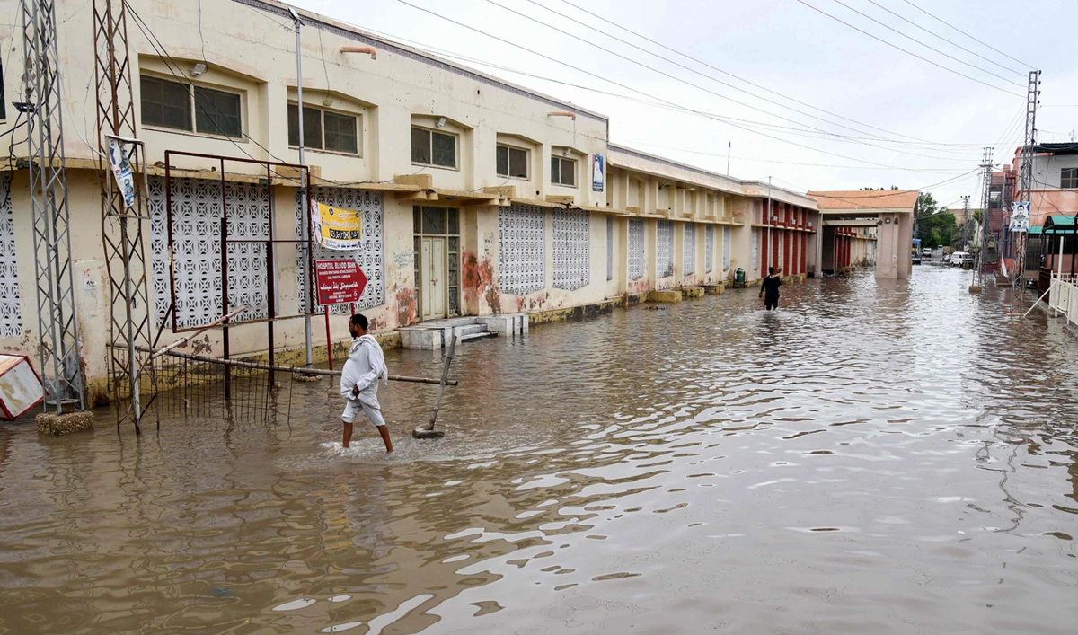 People wade through a flooded street after heavy monsoon rains in Larkana in Sindh province on August 18, 2024. (AFP)