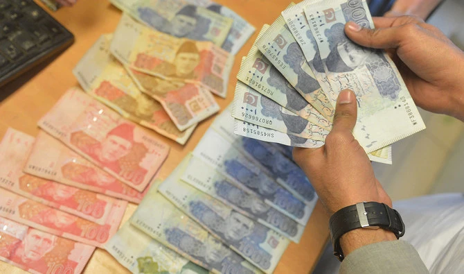 A money changer counts Pakistan's currency at a market in Karachi on January 6, 2023. (AFP/File)