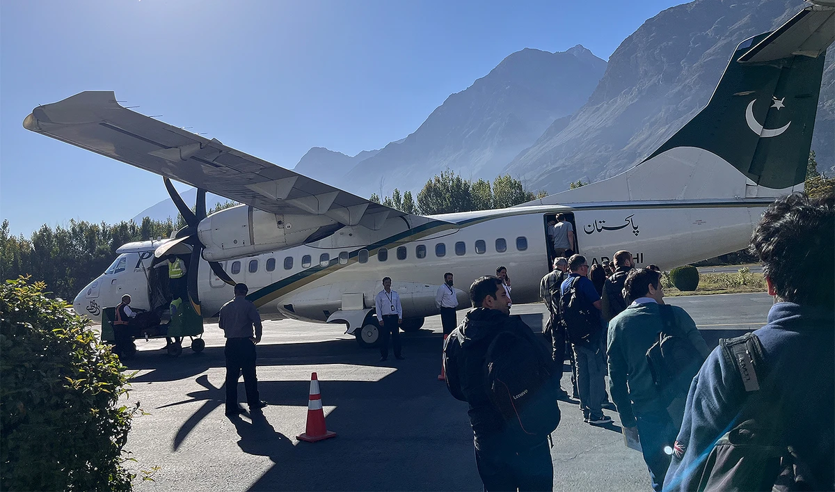 The picture taken on October 11, 2023, shows people boarding a Pakistan International Airlines (PIA) plane at Gilgit Airport in Pakistan's northern Gilgit-Baltistan region. (AN photo by Fatimah Amjad)