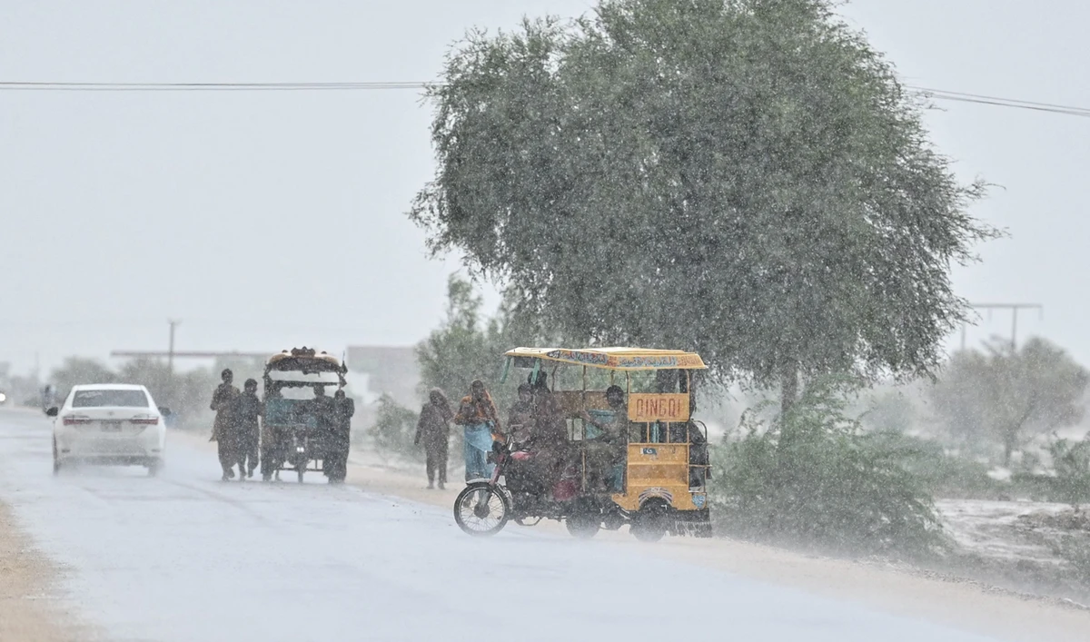 Commuters make their way along a street during rainfall on the outskirts Dadu on August 4, 2024. (AFP/File)