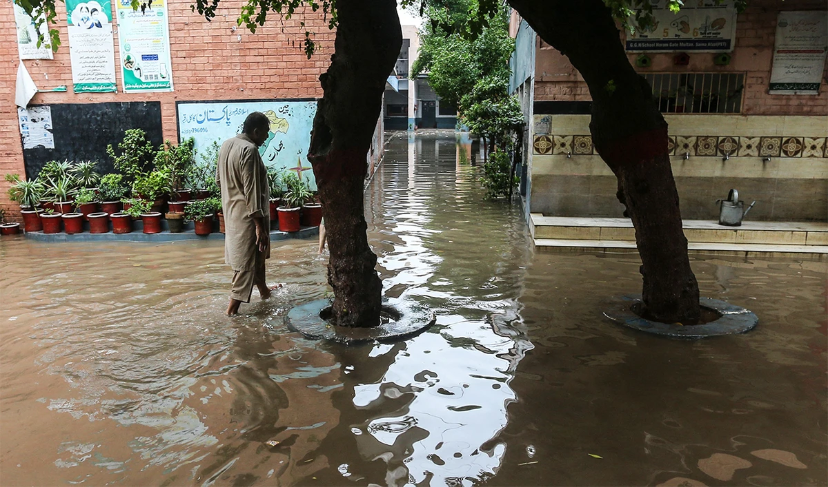 A man walks through floodwaters in the compound of a school, temporarily closed after heavy monsoon rains, in Multan on August 28, 2024. (AFP)