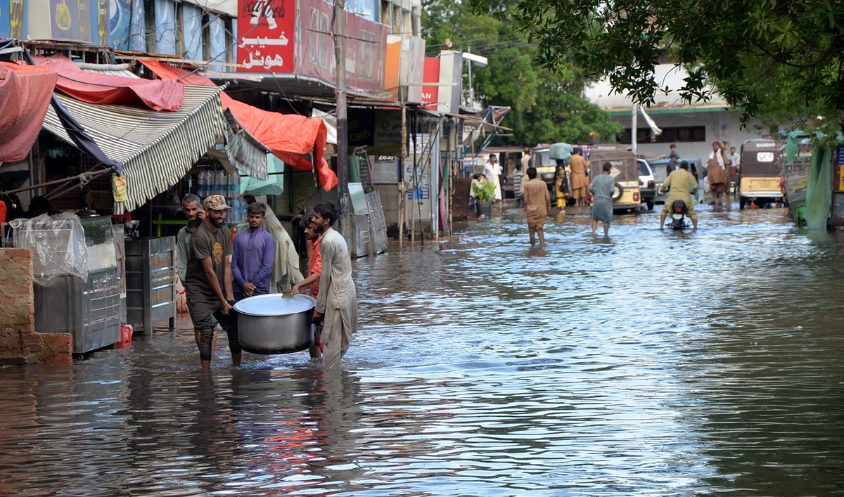 People wade through a flooded road caused by heavy monsoon rain, in Hyderabad, Pakistan on August 30, 2024. (AP)