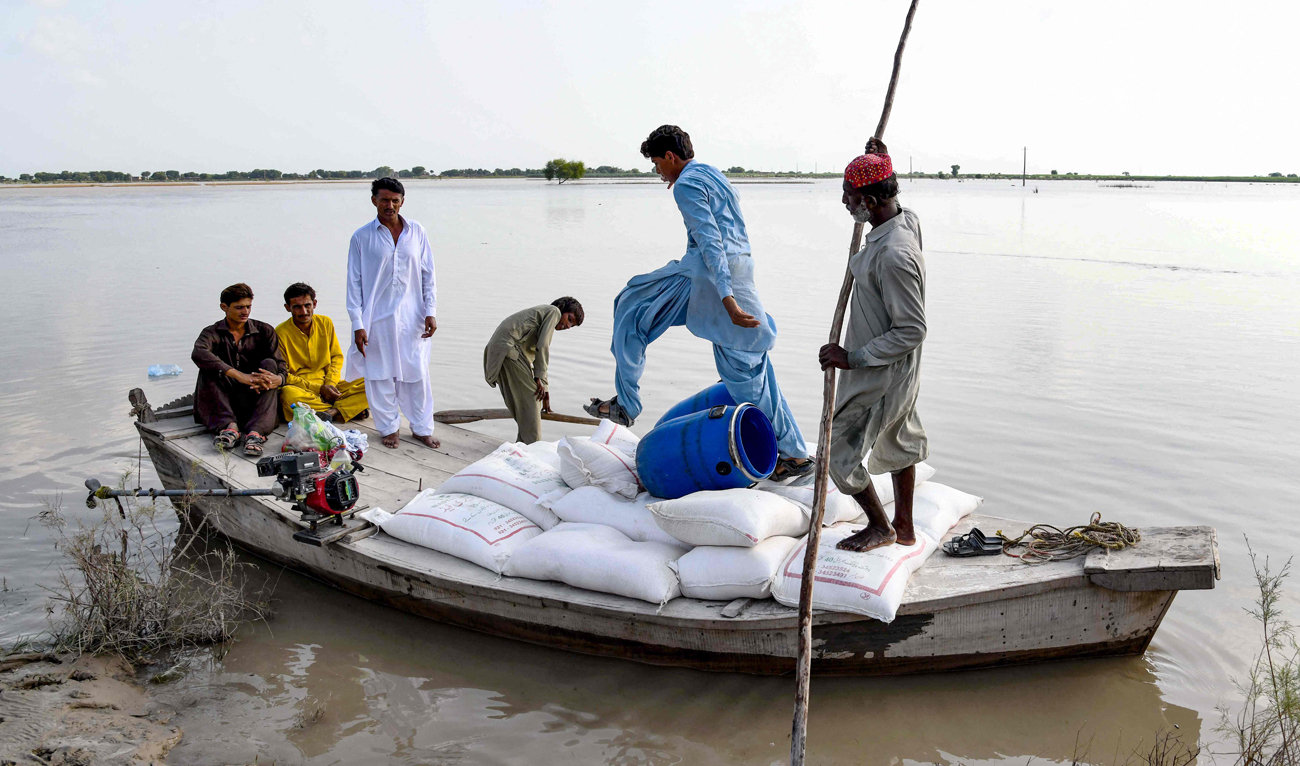 Villagers ferry bags of flour for their flood affected family members after heavy monsoon rains on the outskirts of Larkana, Sindh province on August 31, 2024. (AFP)