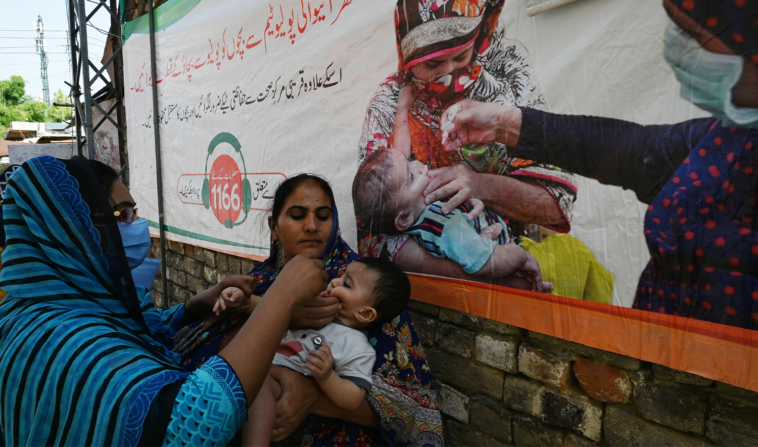 A health worker (L) administers polio vaccine drops to a child during a polio vaccination door-to-door campaign at a low-income residential area in Islamabad on September 21, 2020. (AFP/File)