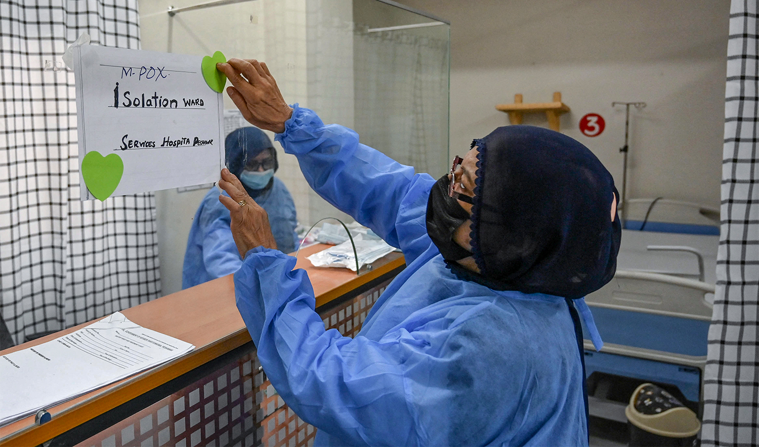 A health worker install a poster indicating an isolation ward prepared for mpox patients at the Police and Services hospital in Peshawar on August 20, 2024. (AFP/File)