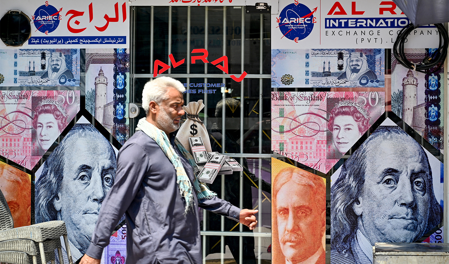 A man walks past a currency exchange shop in Rawalpindi on June 12, 2024. (AFP/File)