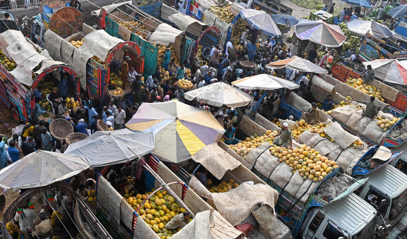 Traders and customers crowd at a wholesale fruit market in Lahore on September 26, 2024. (AFP)
