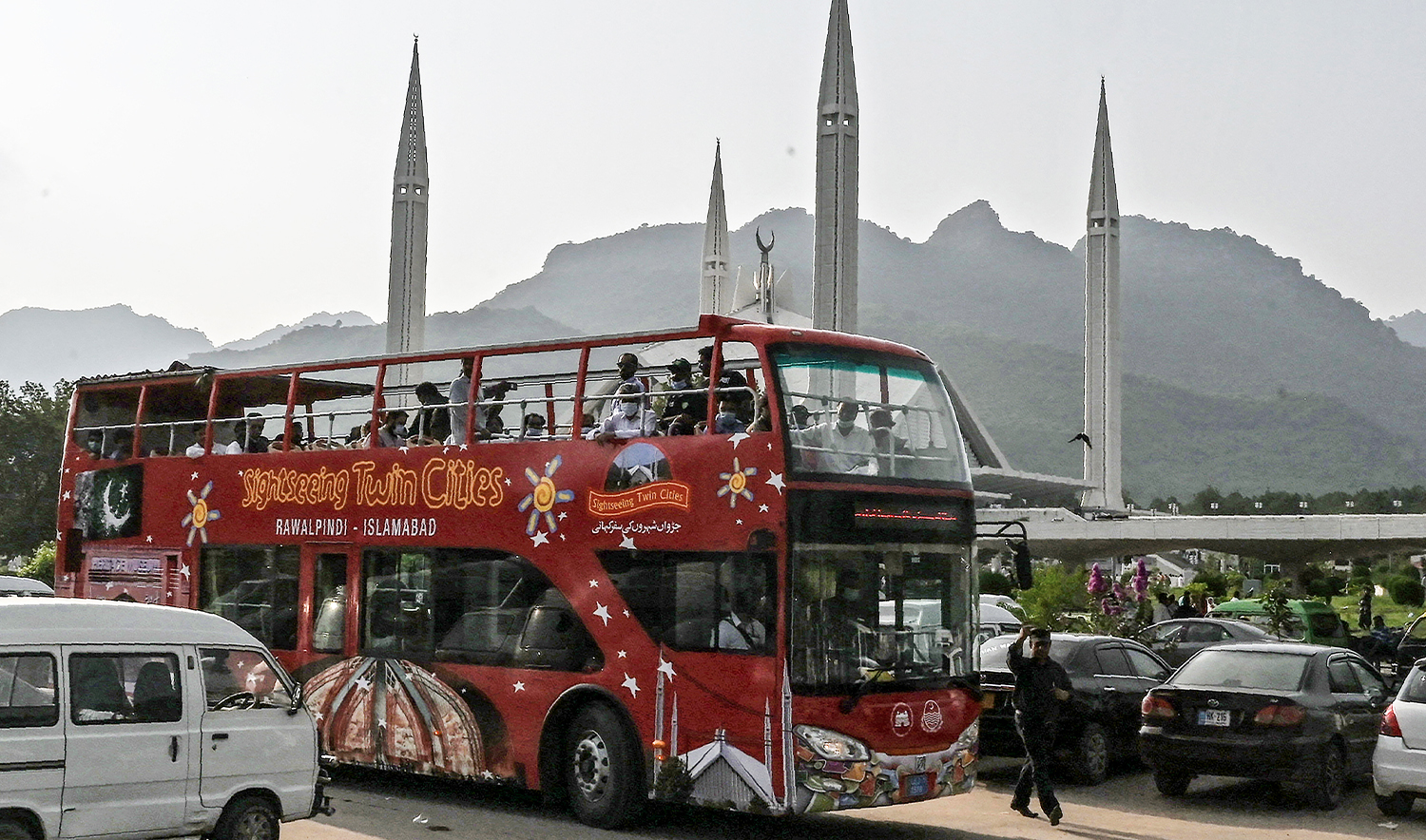 Government and media officials travel in a Rawalpindi-Islamabad colourful tourist double-decker bus in front of the grand Faisal Mosque during a test driving in Islamabad on August 15, 2020. (AFP/File)