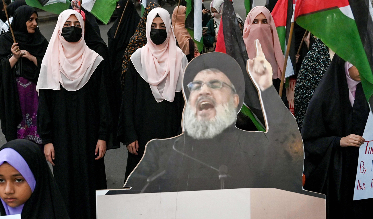Shiite Muslims carrying Palestinian national flags stand beside a portrait of slain Lebanese Hezbollah chief Hassan Nasrallah, during an anti-Israel protest in Lahore on September 28, 2024. (AFP)