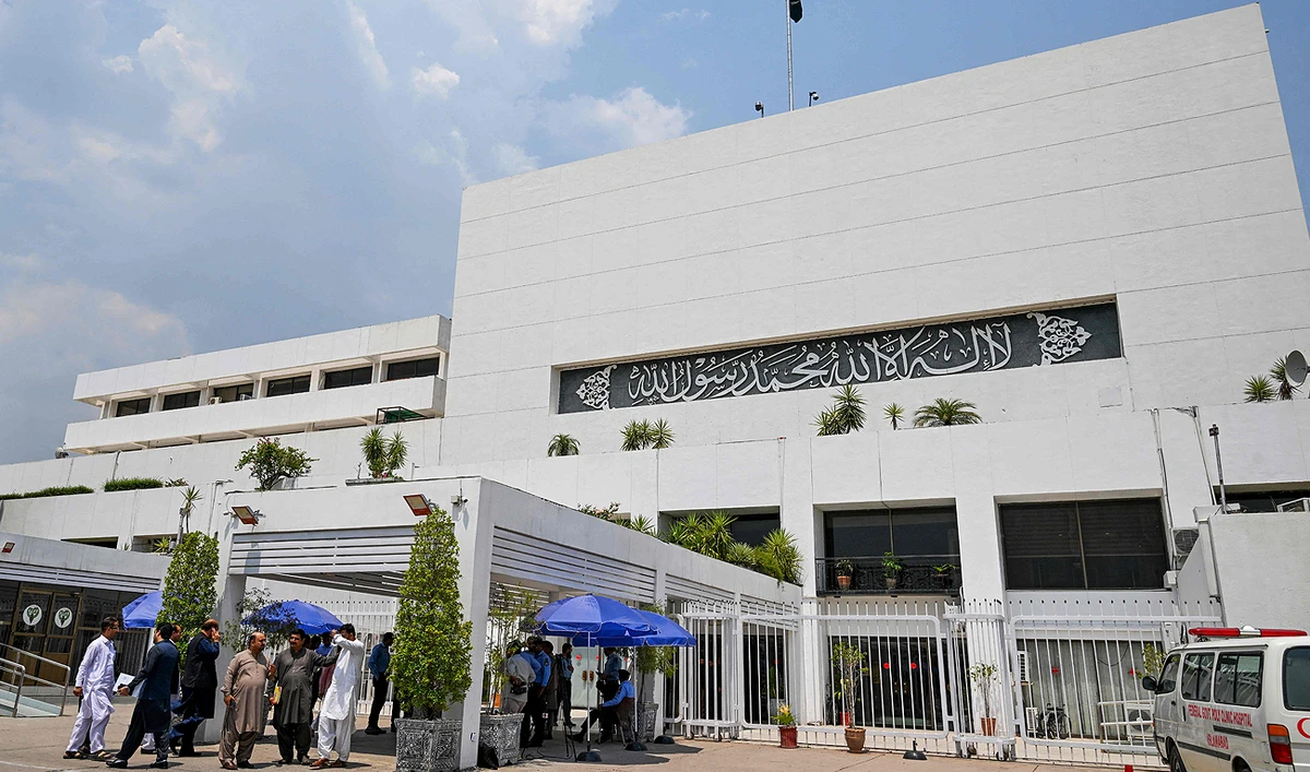 People stand outside the Parliament house during a budget session in Islamabad on June 26, 2024. (AFP)