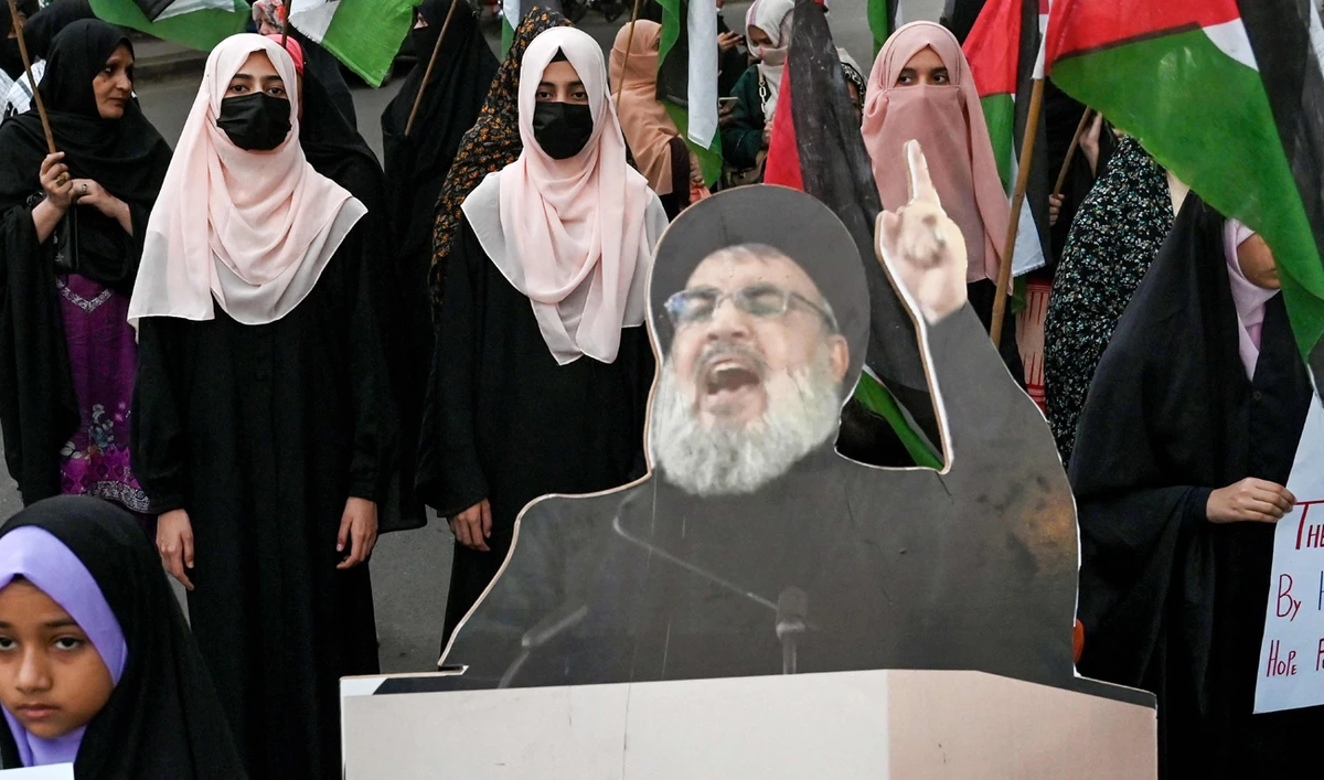 Shiite Muslims carrying Palestinian national flags stand beside a portrait of slain Lebanese Hezbollah chief Hassan Nasrallah, during an anti-Israel protest in Lahore on September 28, 2024. (AFP)