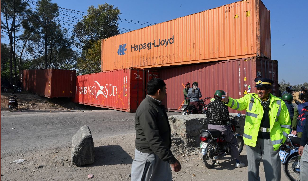 A traffic policeman stands guard infront of a road blocked with shipping containers by authorities on the Islamabad Expressway, during the opposition party Pakistan Tehreek-e-Insaf (PTI) rally called "long march" in Islamabad on November 26, 2022. (AFP/File)