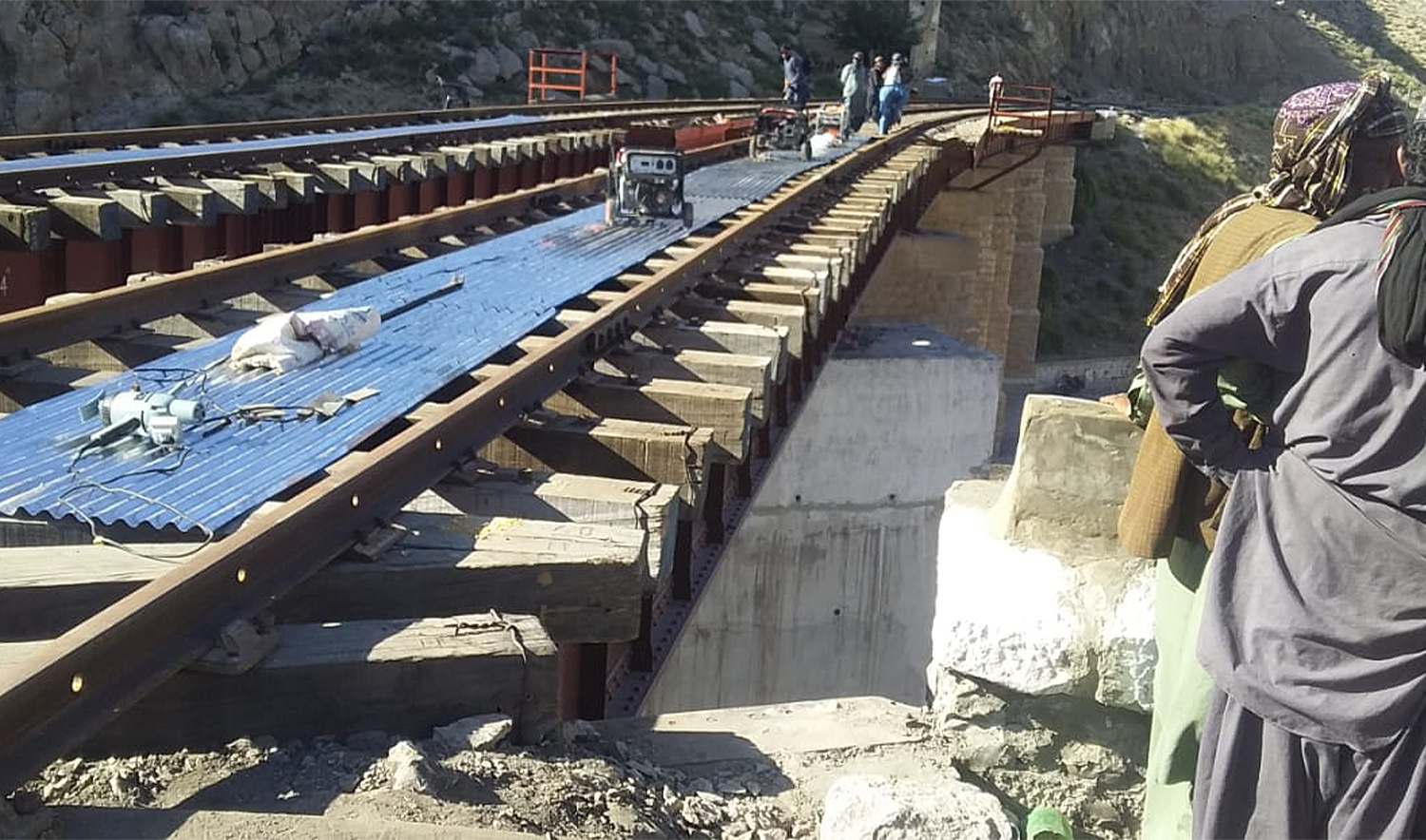 Laborers stand near a newly restored railway bridge at the Bolan Pass on October 11, 2024, which was blown up by armed militants from the outlawed Baloch Liberation Army (BLA) on on August 26, 2024. (Saadullah Akhter)