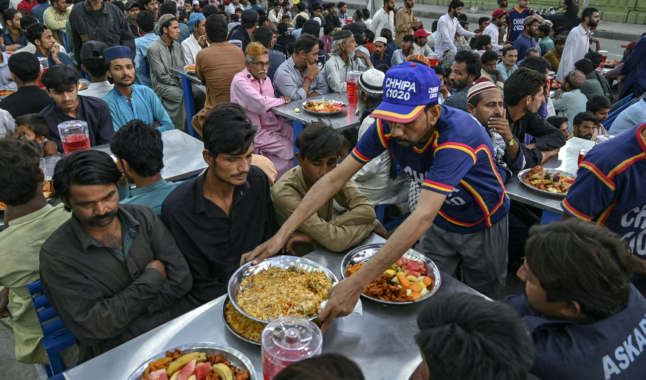 A volunteer distributes food as Muslim devotees wait to break their fast during the Islamic holy month of Ramadan in Karachi on March 13, 2024. (AFP/File)